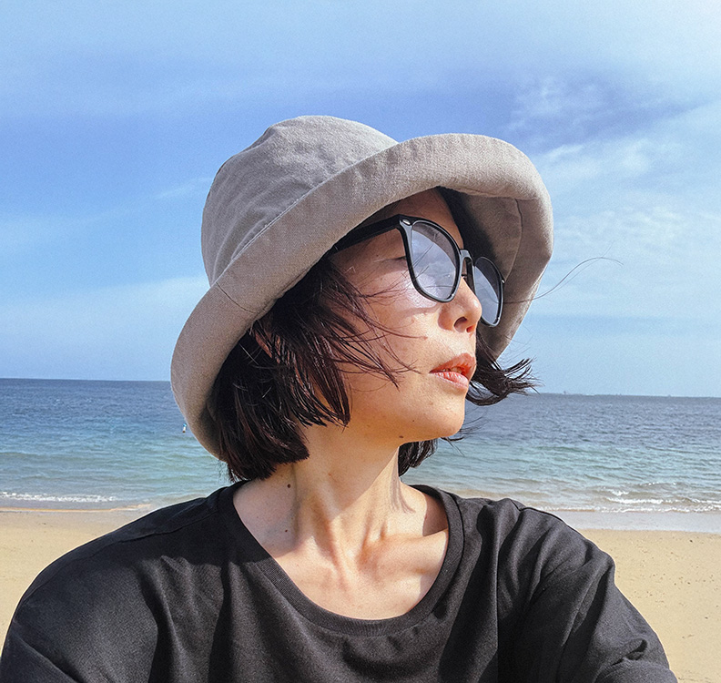 OZNONのプロフィール写真。バリ島のビーチにて帽子とサングラス姿で遠くを見つめる