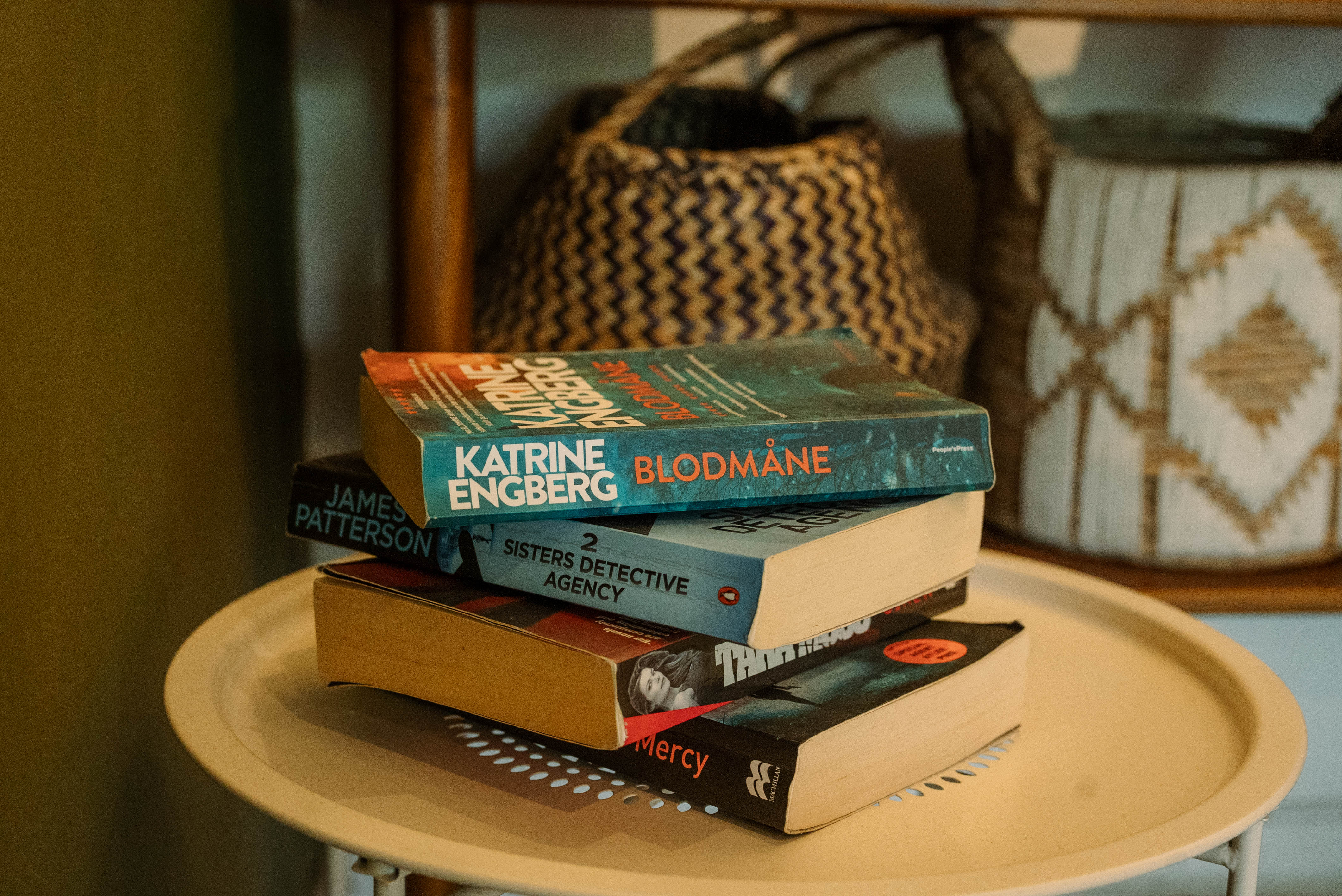 ラウンドテーブルに積まれた洋書と、背景のバスケット。インスピレーションと読書のある日常